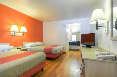 a hotel room with two beds and a desk and a television at Motel 6-El Cajon, CA - San Diego in El Cajon