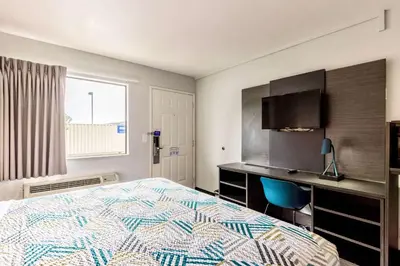 a bedroom with a bed and a desk and a television at Motel 6-Carlsbad, CA - East Near LEGOLAND in Carlsbad