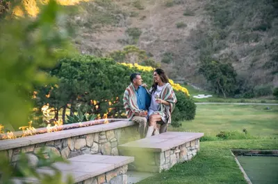 a man and a woman sitting on a stone wall at The Ranch at Laguna Beach in Laguna Beach