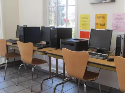 a row of desks with computer monitors and chairs at Motel 6 Hemet in Hemet