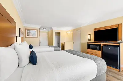 a hotel room with two beds and a flat screen tv at Travelodge by Wyndham San Clemente Beach in San Clemente