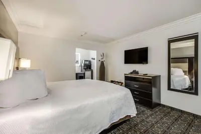 a bedroom with a large white bed and a mirror at Rodeway Inn Old Town Temecula in Temecula