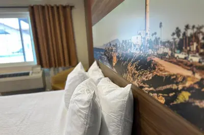 a bed with white pillows and a picture on the wall at Hyland Inn near Legoland in Carlsbad