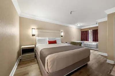 a bedroom with a large bed with a red pillow at Americas Best Value Inn San Clemente Beach in San Clemente