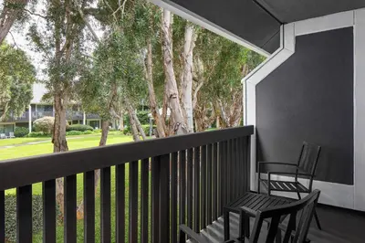 two chairs on a balcony with trees in the background at Carlsbad by the Sea Hotel in Carlsbad