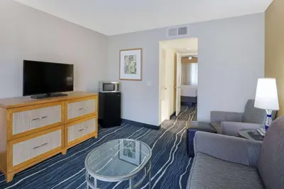 a living room with a couch and a flat screen tv at Ramada by Wyndham Costa Mesa/Newport Beach in Costa Mesa