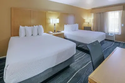 a hotel room with two beds and a desk at Ramada by Wyndham Costa Mesa/Newport Beach in Costa Mesa