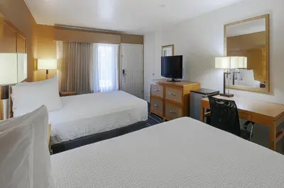 a hotel room with two beds and a desk and a television at Ramada by Wyndham Costa Mesa/Newport Beach in Costa Mesa