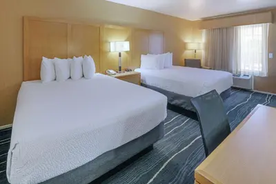 a hotel room with two beds and a desk at Ramada by Wyndham Costa Mesa/Newport Beach in Costa Mesa