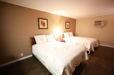 a hotel room with two beds with white sheets at Royal Inn and Suites in Hemet