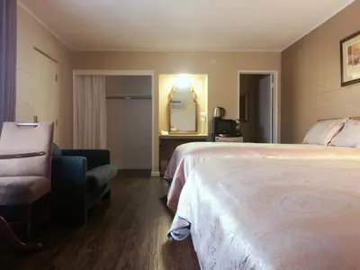 a hotel room with a bed and a chair and a mirror at Royal Inn and Suites in Hemet