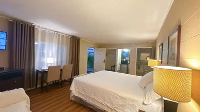 a hotel room with a bed and a desk and a table at Royal Inn and Suites in Hemet