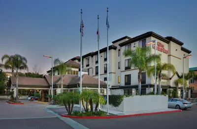 a building with palm trees in front of a street at Hilton Garden Inn San Diego Del Mar in San Diego