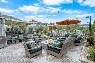 a patio with couches and tables and an umbrella at Hilton San Diego/Del Mar in San Diego
