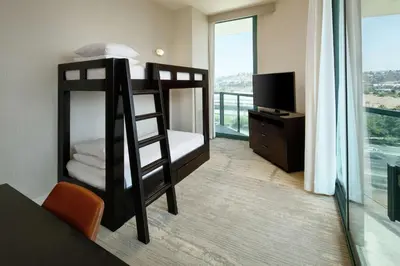 a bedroom with bunk beds and a balcony with a television at DoubleTree By Hilton San Diego Hotel Circle in San Diego