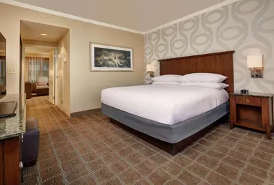 a hotel room with a large bed and a television at Embassy Suites by Hilton San Diego La Jolla in San Diego