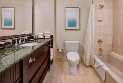 a bathroom with a toilet and a sink and a tub at Embassy Suites by Hilton San Diego La Jolla in San Diego