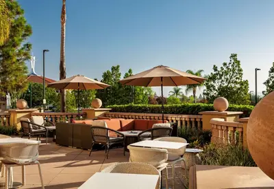 an outdoor patio with tables and chairs and umbrellas at Hilton Garden Inn San Diego/Rancho Bernardo in Rancho Bernardo