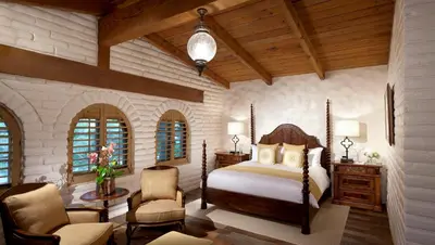 a bedroom with a bed and chairs in a room at Rancho Valencia Resort and Spa in Rancho Santa Fe