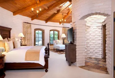 a bedroom with a large bed and a stone wall at Rancho Valencia Resort and Spa in Rancho Santa Fe
