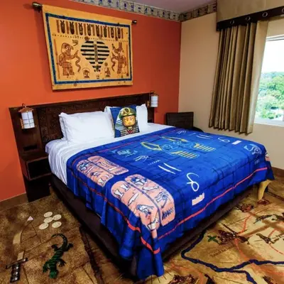 a bedroom with a large bed with a blue blanket at LEGOLAND California Hotel and Castle Hotel in Carlsbad