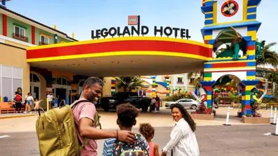 a man and two children standing in front of a hotel at LEGOLAND California Hotel and Castle Hotel in Carlsbad