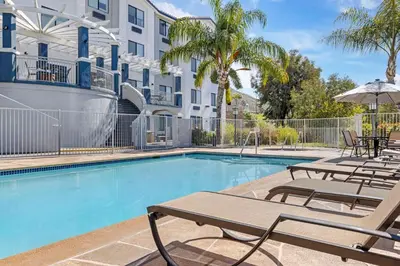a swimming pool with tables and chairs next to a building at Best Western Plus Lake Elsinore Inn & Suites in Lake Elsinore