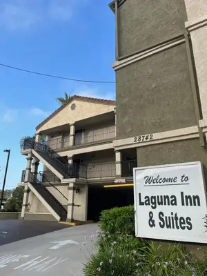 a sign in front of a building with a lauren inn and suites at Laguna Inn and Suites in San Juan Capistrano