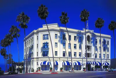 a white building with palm trees in front of it at Grande Colonial La Jolla in San Diego