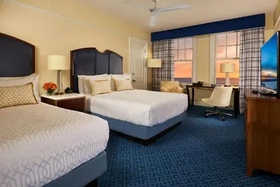 a hotel room with two beds and a desk at Grande Colonial La Jolla in San Diego