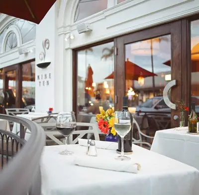 a table with two wine glasses and flowers on it at Grande Colonial La Jolla in San Diego