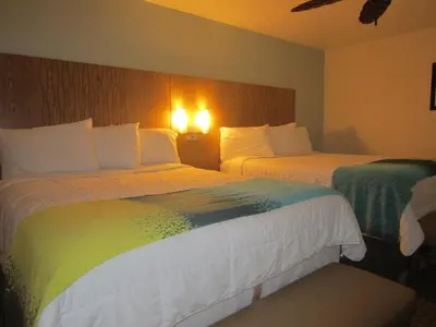 a hotel room with two beds and lights on the wall at PB Surf Beachside Inn in San Diego