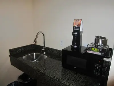a kitchen counter with a sink and a microwave at PB Surf Beachside Inn in San Diego