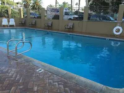a large blue swimming pool with chairs around it at PB Surf Beachside Inn in San Diego