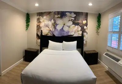 a bedroom with a large white bed with a painting at Escondido Inn in Escondido