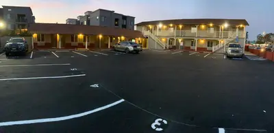 a parking lot with cars parked in front of a building at Escondido Inn in Escondido