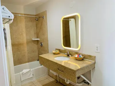 a bathroom with a sink and a mirror and a tub at Escondido Inn in Escondido