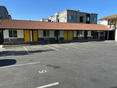 a building with yellow doors in a parking lot at Escondido Inn in Escondido