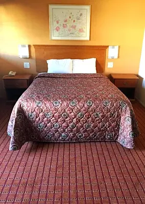 a bed in a hotel room with a red bedspread at Harvey's Motel SDSU La Mesa San Diego in San Diego