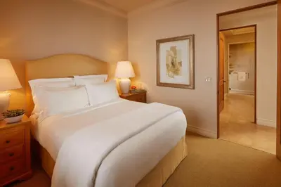 a bedroom with a large white bed and a hallway at The Resort at Pelican Hill in Crystal Cove