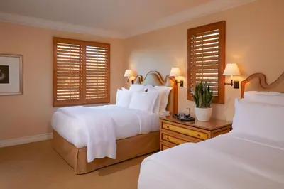 a bedroom with two beds and two windows at The Resort at Pelican Hill in Crystal Cove