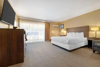 a hotel room with a bed and a flat screen tv at Best Western Oceanside Inn in Oceanside