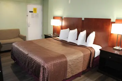 a hotel room with a large bed and a chair at Rancho California Inn Temecula in Temecula