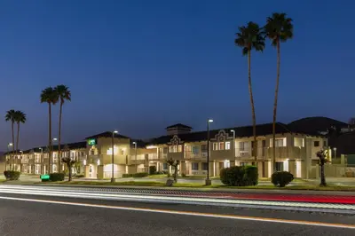 a row of apartment buildings with palm trees at night at Quality Inn Lake Elsinore I-15 in Lake Elsinore