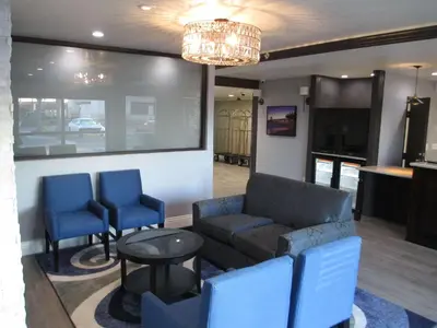 a living room with a couch and two blue chairs at Best Western Plus Diamond Valley Inn in Hemet