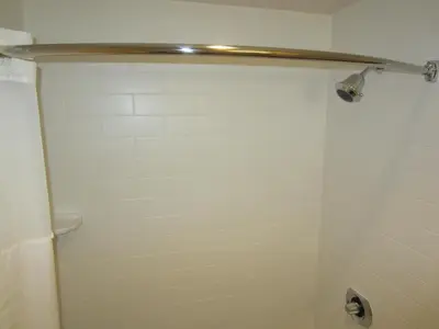a bathroom with a shower with a white tiled wall at Old Town Inn in San Diego