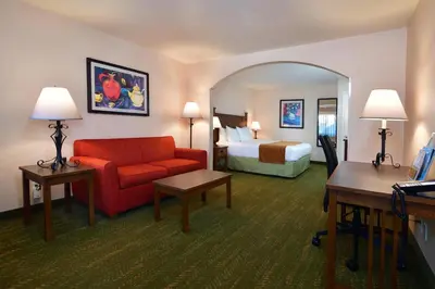 a hotel room with a red couch and a bed at Lamplighter Inn & Suites at SDSU in San Diego