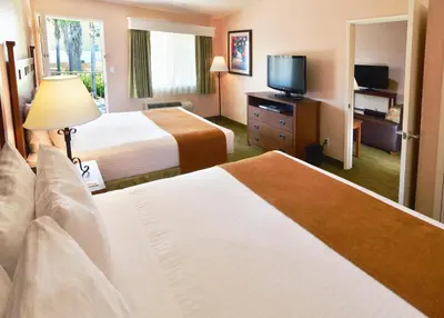 a hotel room with two beds and a flat screen tv at Lamplighter Inn & Suites at SDSU in San Diego