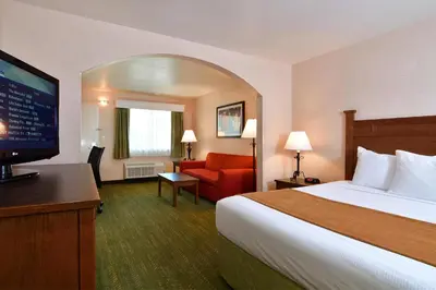 a hotel room with a bed and a flat screen tv at Lamplighter Inn & Suites at SDSU in San Diego