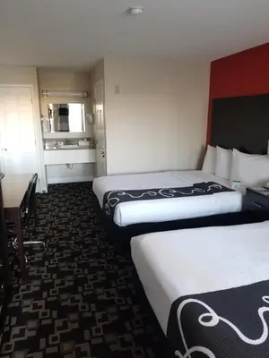a hotel room with two beds and a desk at Ramada by Wyndham Oceanside in Oceanside